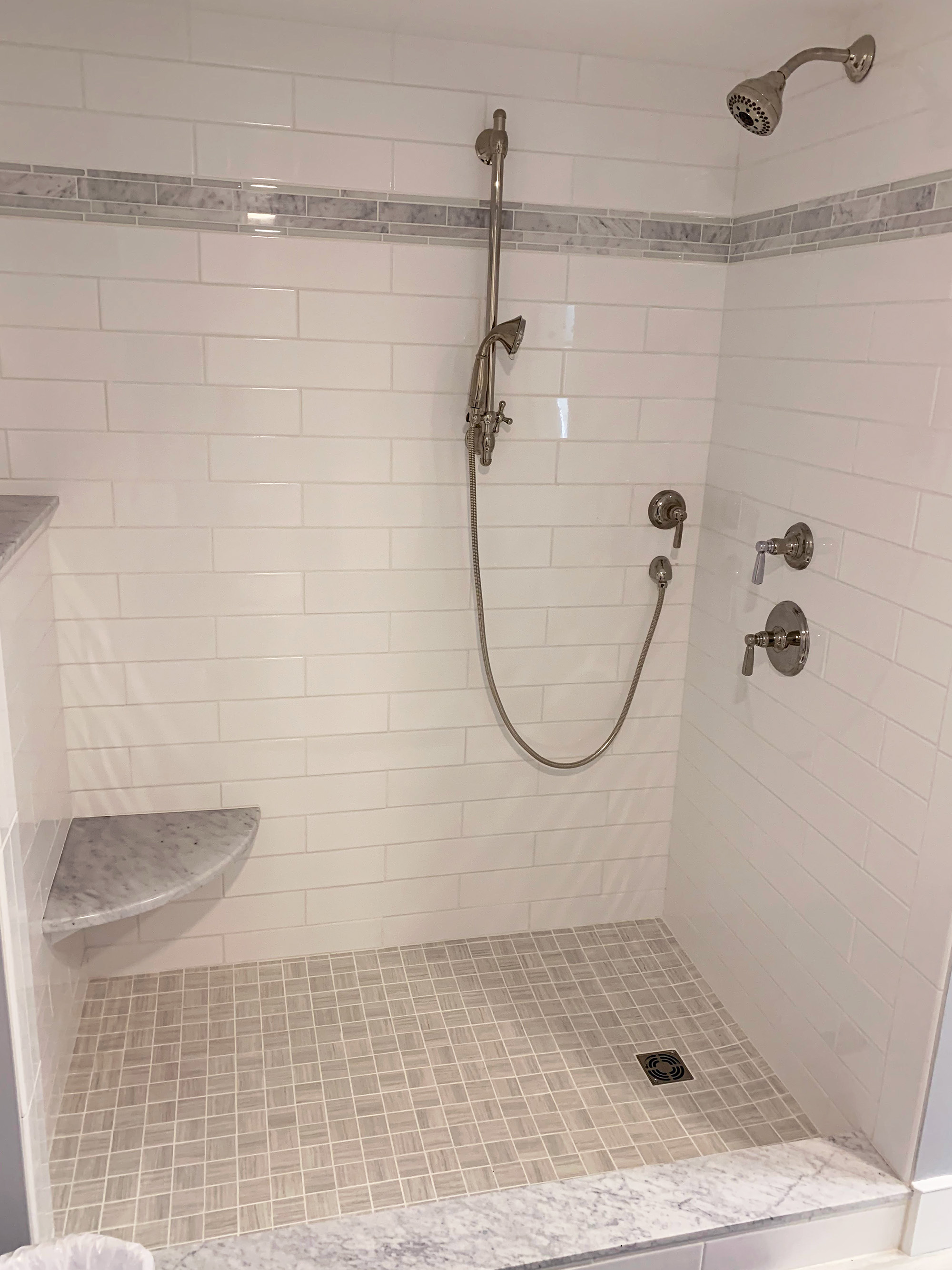 Walk-in shower with white tile and a glass door.