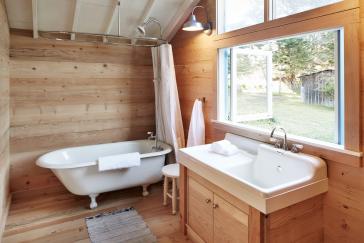 Bathroom with cabin vibes, including wood wall treatment, wood flooring, views, and a claw foot tub.