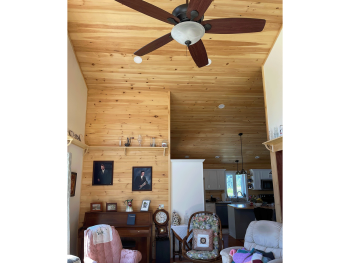Wood walls and ceiling in the living room with fan.