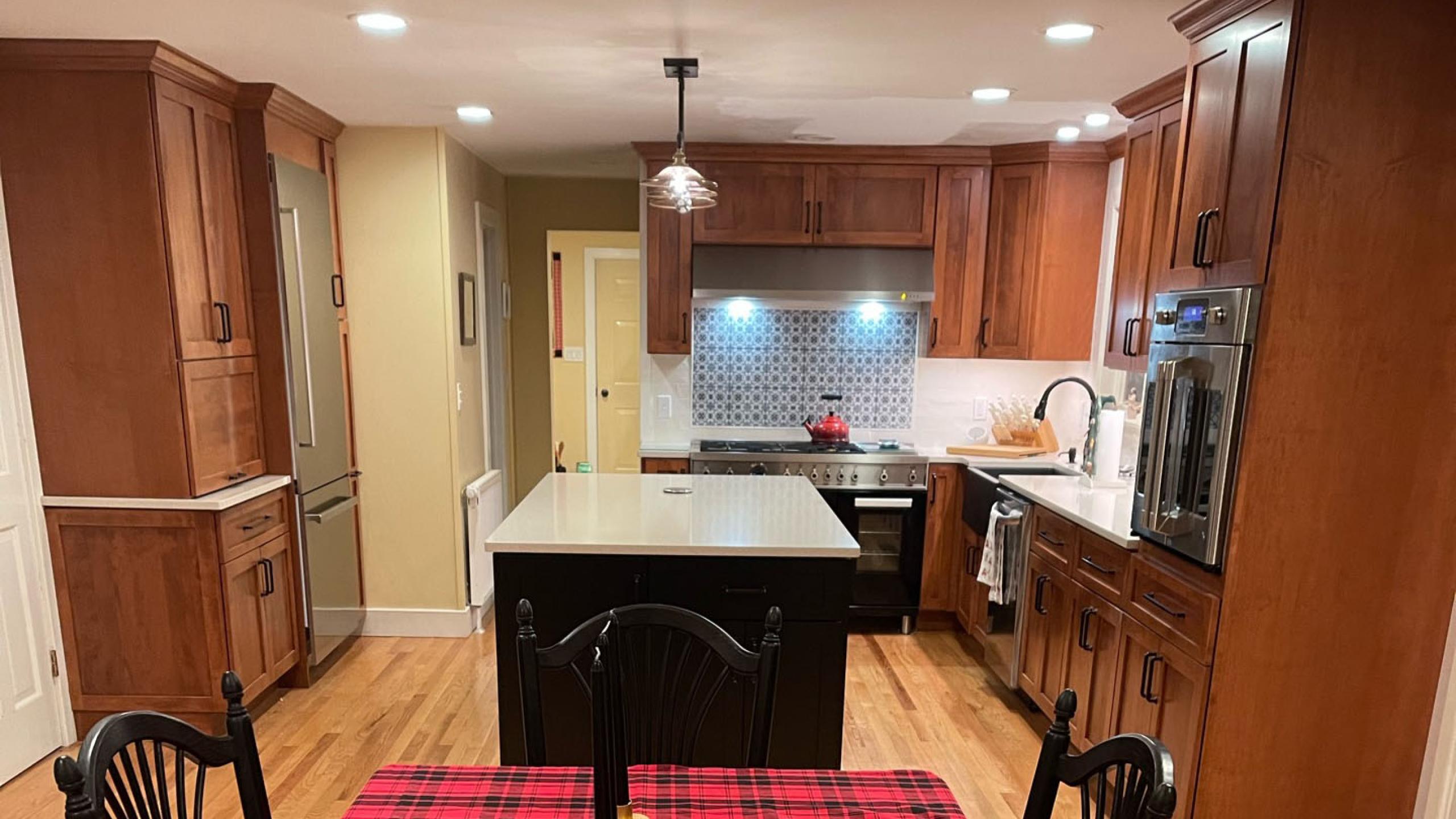 Kitchen remodel with island, cabinets, floor refinishing, appliances, and countertops.