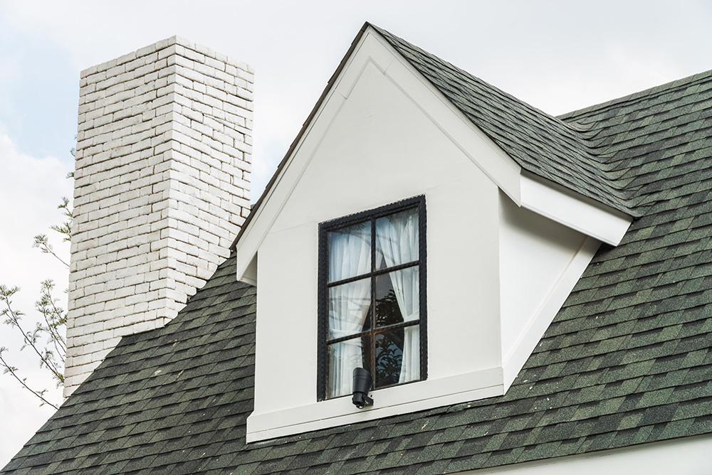 Shingle roofing with a New England cottage, white brick and a white chimney. 