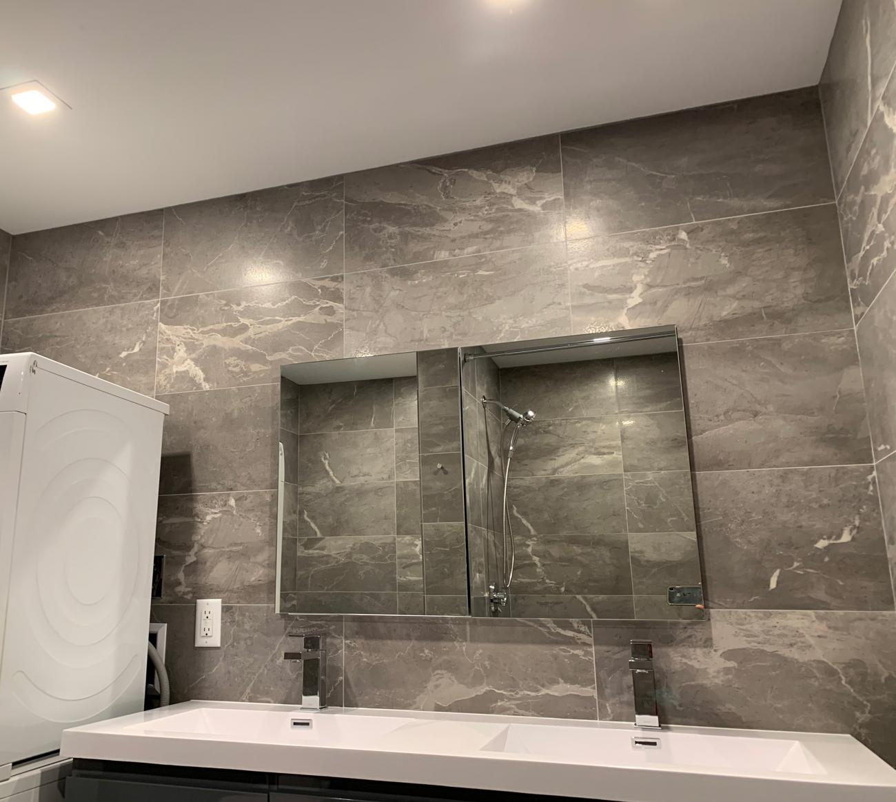 Bathroom vanity with marble and tiled walls.