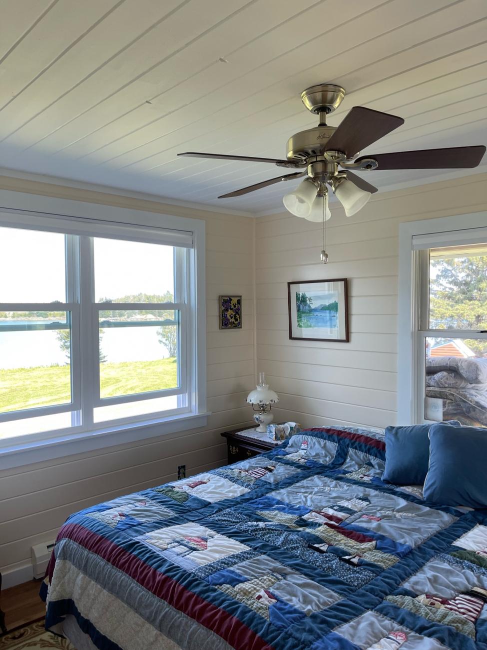 Bedroom with painted shiplap wood walls looking out onto the Maine coast.