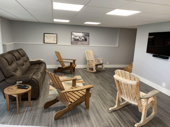 Media room with drop ceiling and wood floors. The room is decorated with a cozy couch and Adirondack chairs