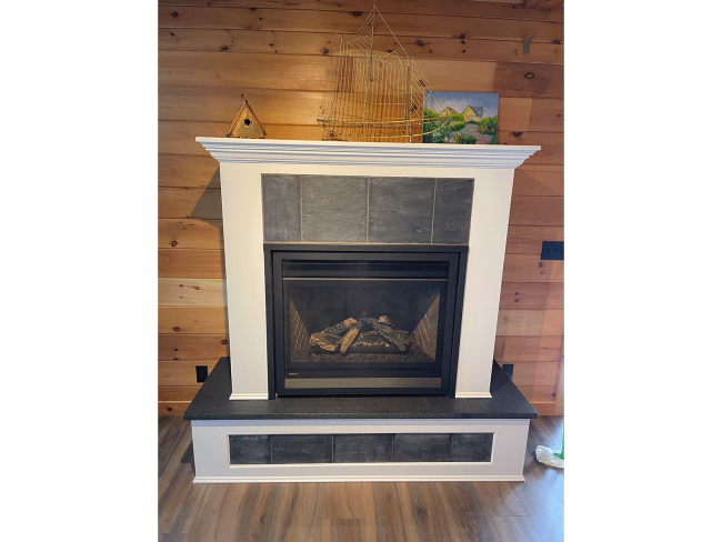 Front view of custom built wood fireplace surround with slate insets in the hearth and mantel.