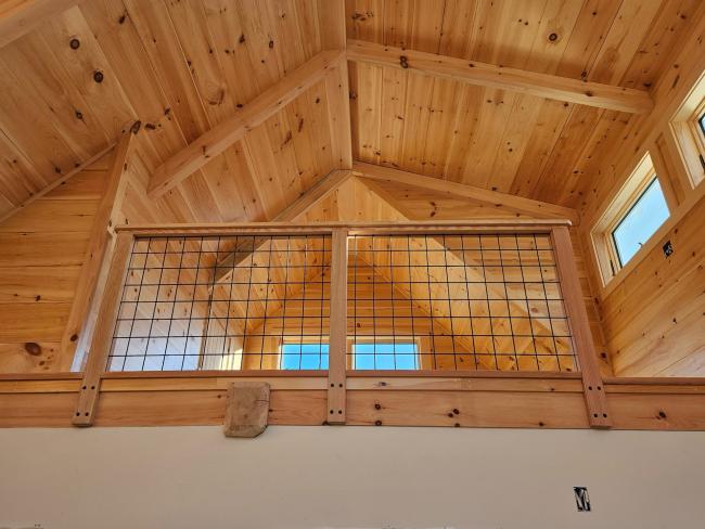 View of loft bedroom from the first floor with exposed wood beams.