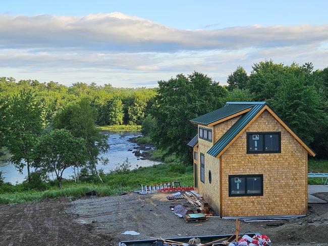 Wide angle view of cabin on waterfront while under construction and near completion.