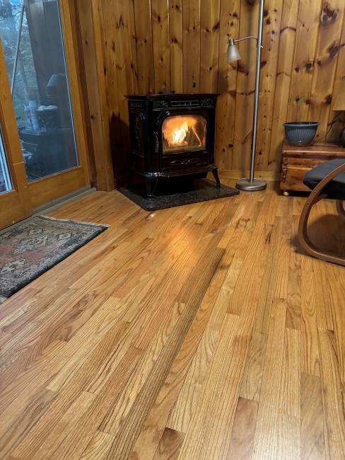 Oak flooring in a Maine cabin with a wood burning stove blazing.