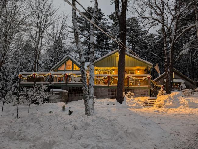 Remodeled cabin on Mt. Desert at Christmas time with string lights and snow on the ground.