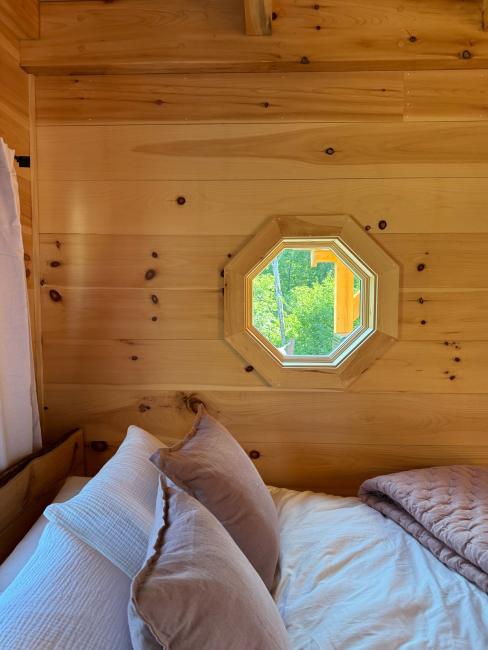 Bedroom with custom carpentry octagonal window and wood shiplap siding.