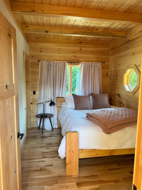 Cabin bedroom with white linens and wood details throughout.