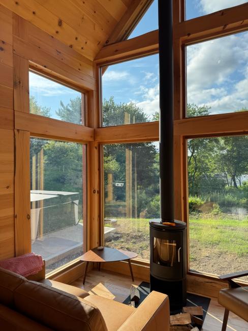 Glass sunroom constructed in Maine cabin with wood-burning stove.