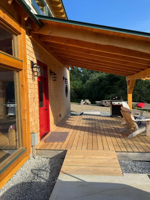Patio and large deck awning constructed for The Willow cabin with a red front door.