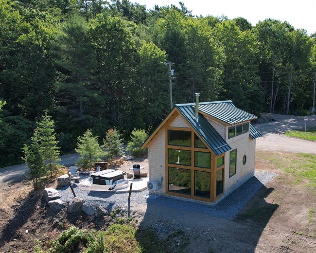 Aerial view of The Willow shingle sided cabin with metal roof and large wood framed windows.