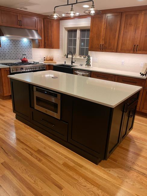 Wide angle view of kitchen with island, sink, cabinets, countertops, and range.