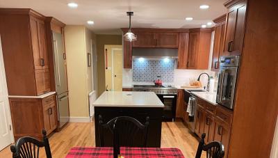 Kitchen remodel with wood cabinets and floors, as well as new kitchen island and dual-fuel range.