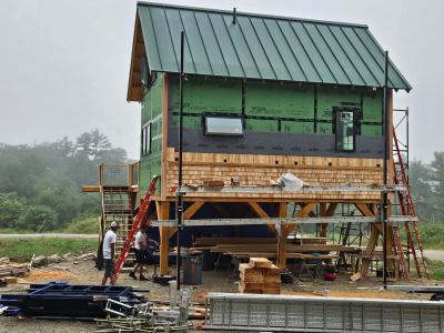 Home under construction with metal roof and wood shingle siding.